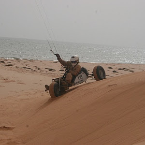 Kite Buggy navigating down a sand dune with the ocean in the background